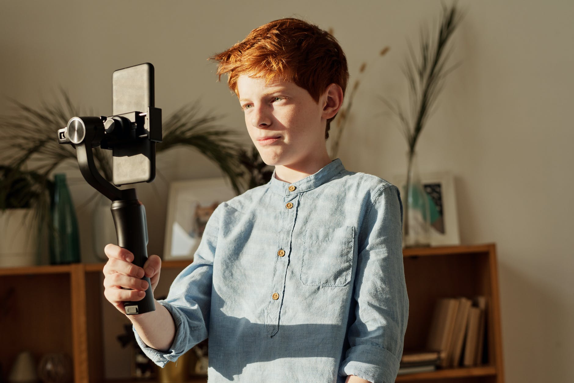 boy in blue dress shirt holding black selfie stick